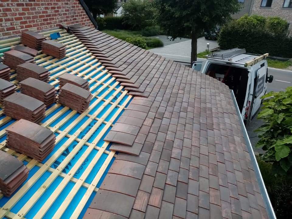 Dakpannen worden gelegd op nieuwe panlatten en onderdakfolie